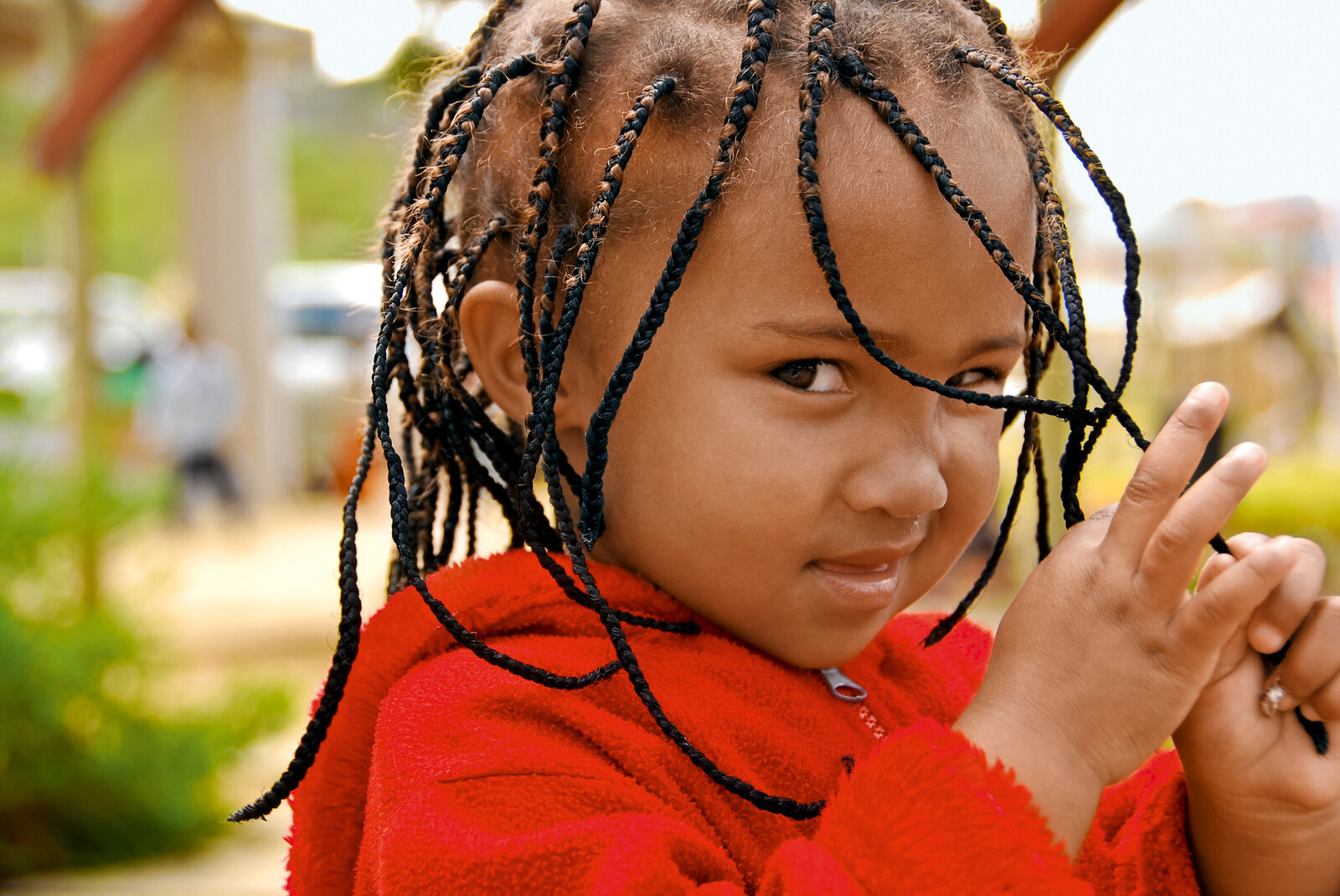 The African girl looks sideways into the camera and twists her braids. She is involved in the For Smiling Children project. This is supported by the Grand Resort Bad Ragaz, a star hotel in Switzerland.