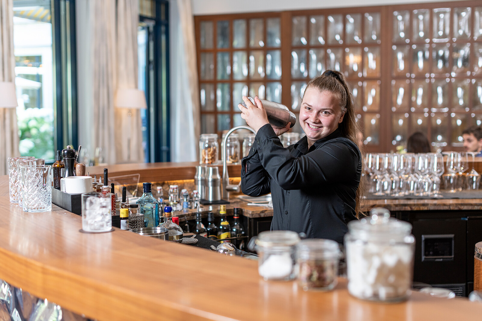 The restaurant apprentice stands at the bar and mixes a drink. The bar is located in the Hotel Grand Resort Bad Ragaz, a star hotel in Switzerland.